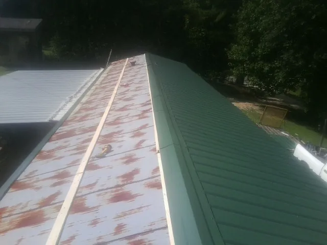 Old rusted panels beside newly installed green metal roofing — Wind Damage Roof Repair by Roofing Brothers in Paonia