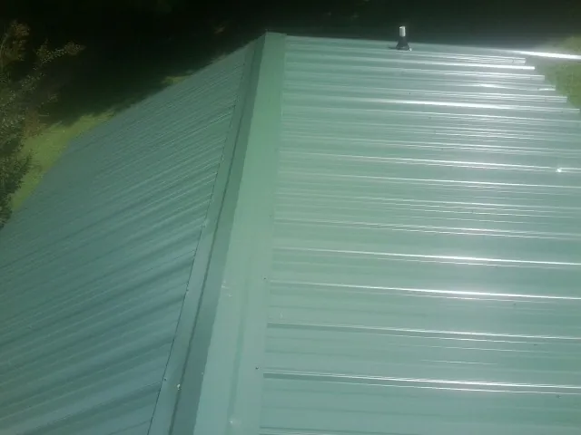 New green metal panels meeting at the ridge of a roof — Flat Roof Repair work by our crew in Paonia