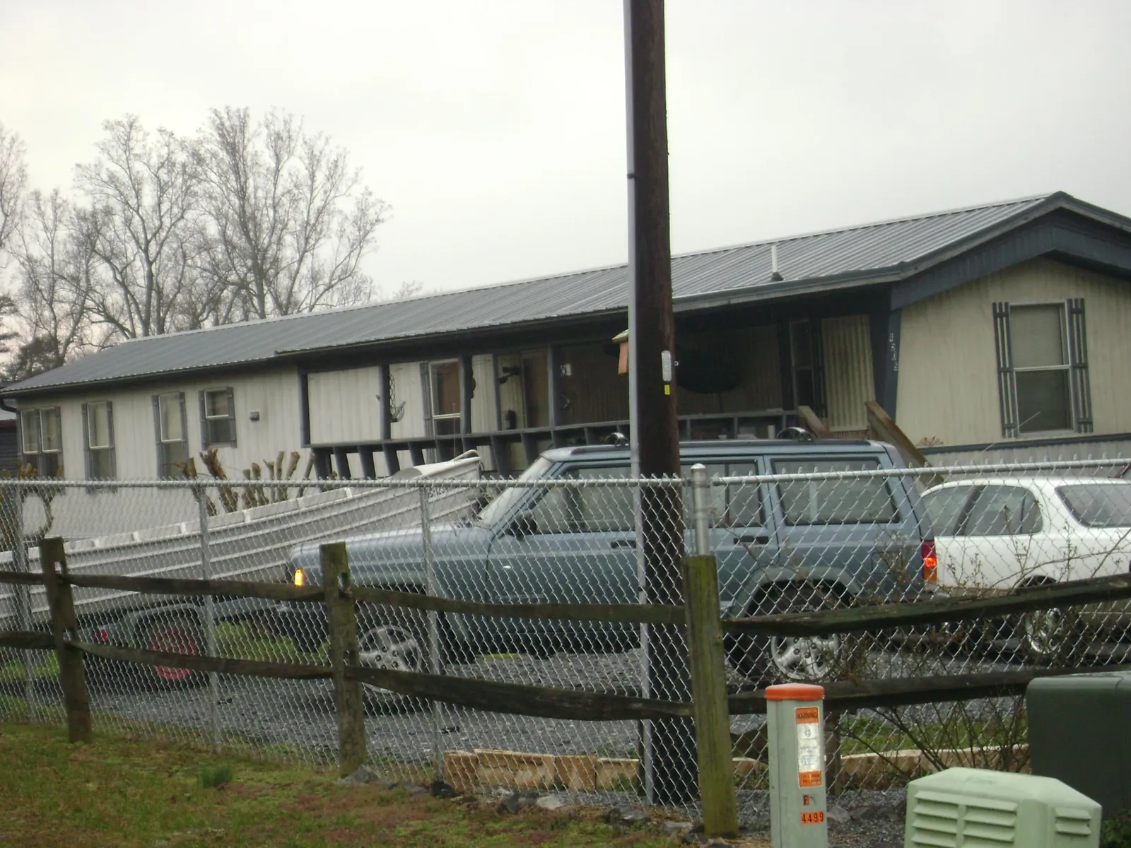 Dark metal roof on a long single story building behind a chain link fence in Paonia