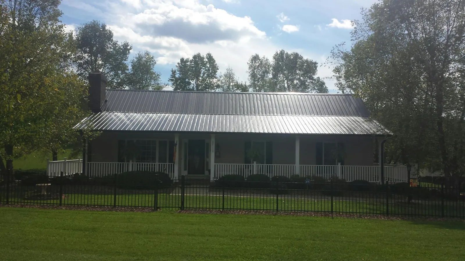 Gray metal roof on a brick ranch with a full width front porch — Gutter Guard Installation work by our crew in Paonia