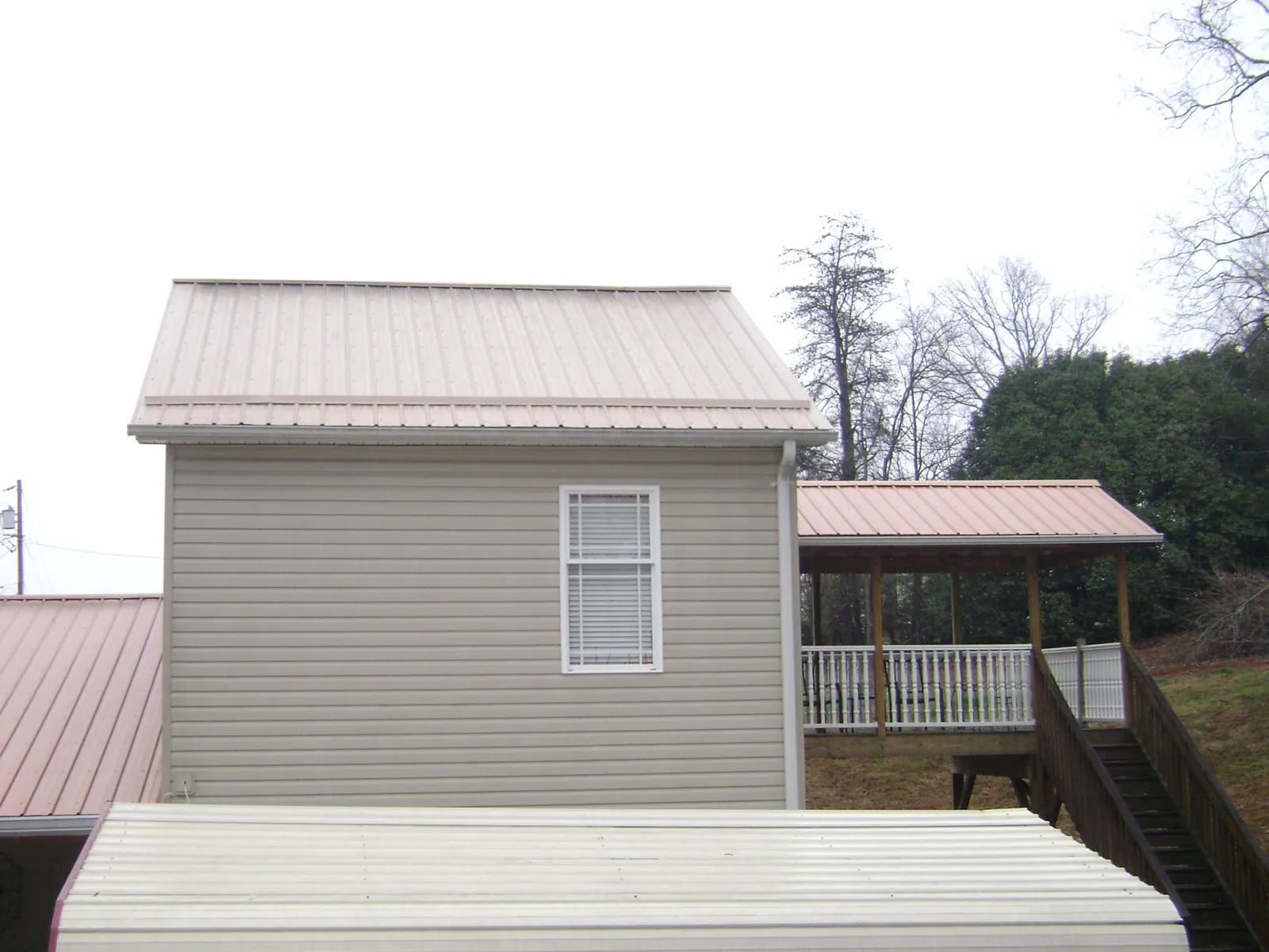Tan metal roofs on a two story addition and attached porch, from a Roof Replacement job in Paonia