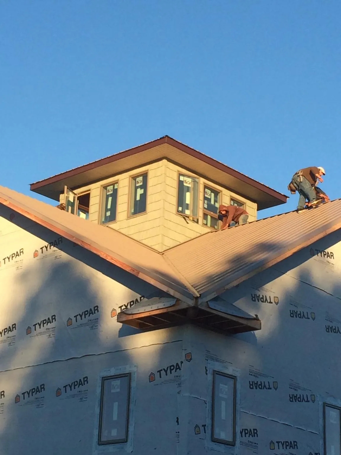 Roofers working around a rooftop cupola on a new metal roof at sunset — Roof Waterproofing in Paonia by Roofing Brothers